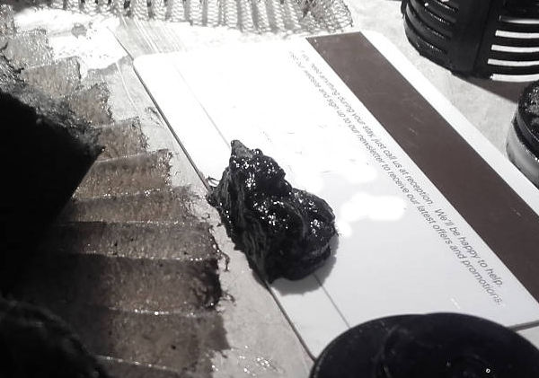 Pile of sludge positioned next to a used Haldex filter which has been cut open and rolled out